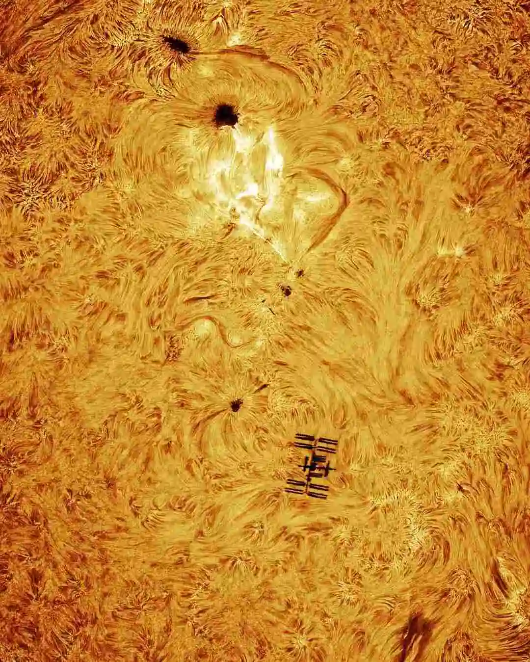 ISS transiting the Sun, framed perfectly against an flaring solar region