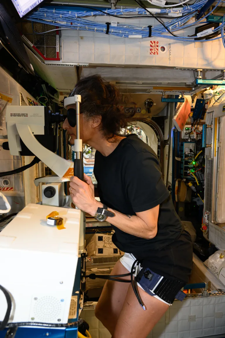 Astronaut Sunita Williams taking an eye test aboard the ISS wearing a tight thigh cuff.